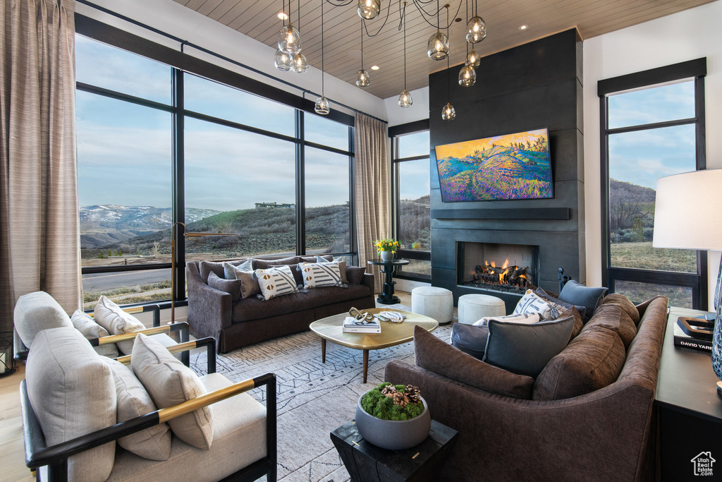 Living room with a warm lit fireplace, wood ceiling, and recessed lighting