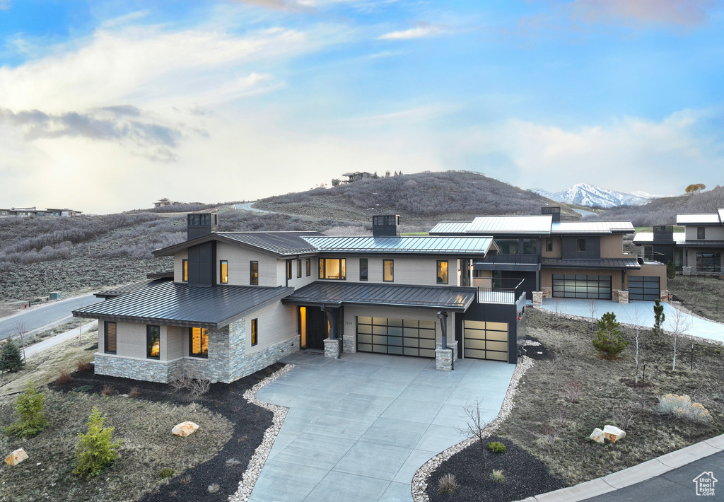 Contemporary house with stone siding, a mountain view, a standing seam roof, driveway, and metal roof