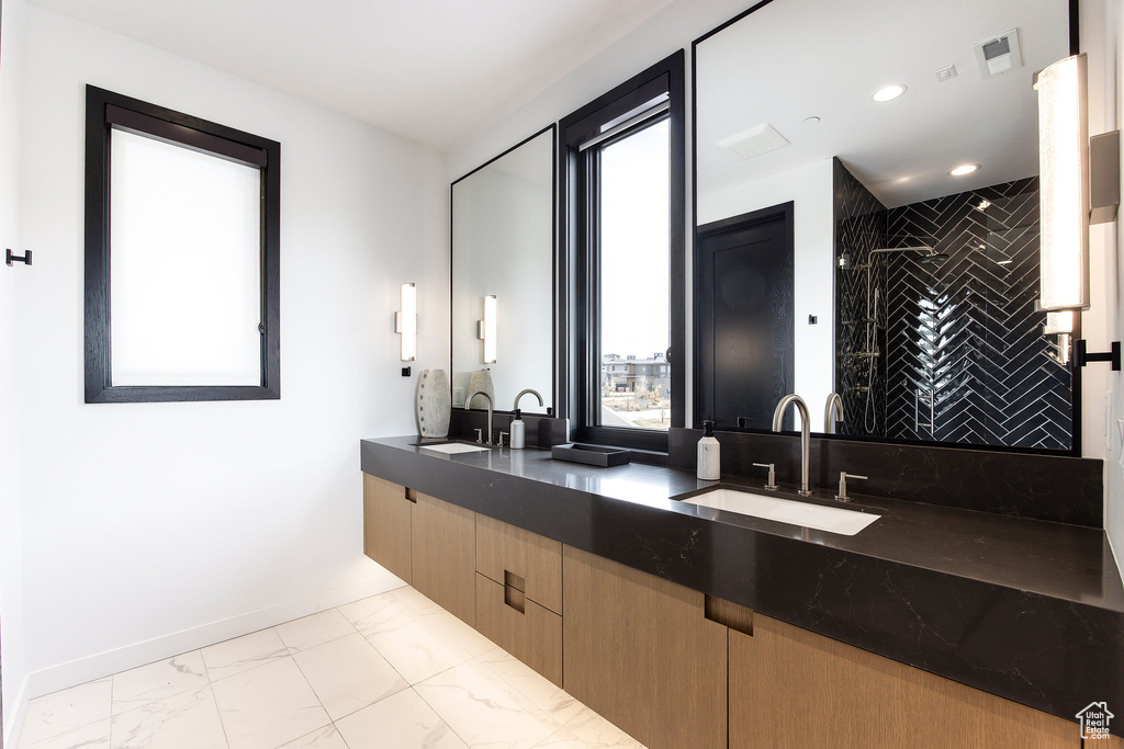 Bathroom with marble look tiles, a stall shower, double vanity, recessed lighting, and baseboards