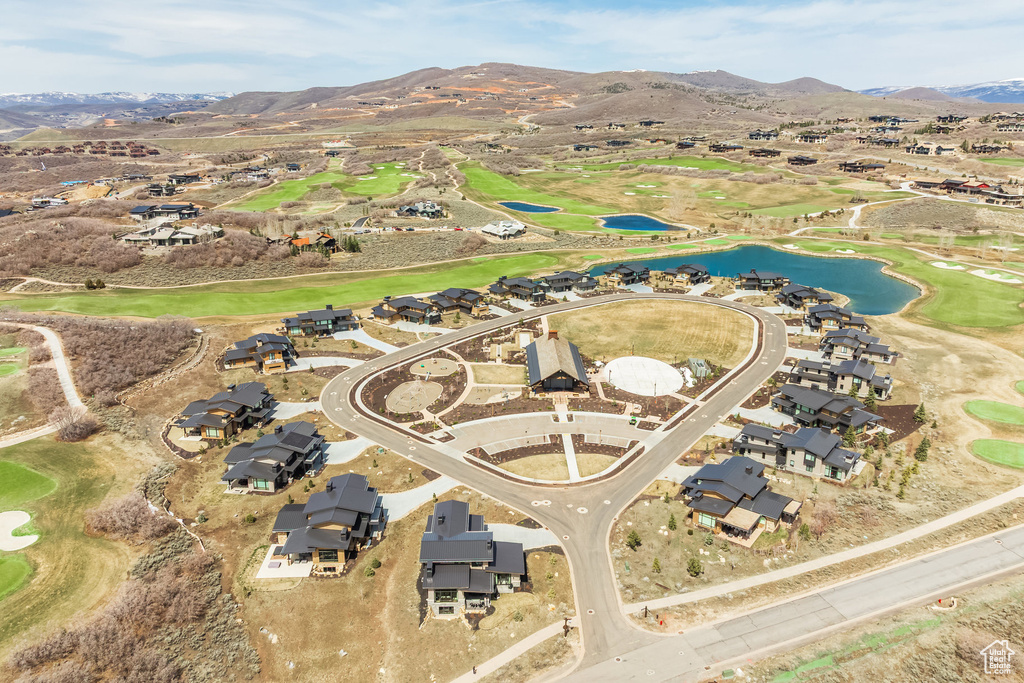 Aerial view of property's location featuring a water and mountain view, a local golf course, and nearby suburban area