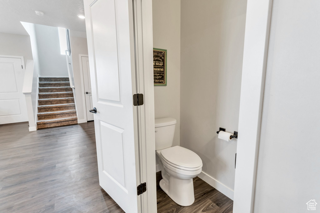 Bathroom featuring baseboards, toilet, and wood finished floors