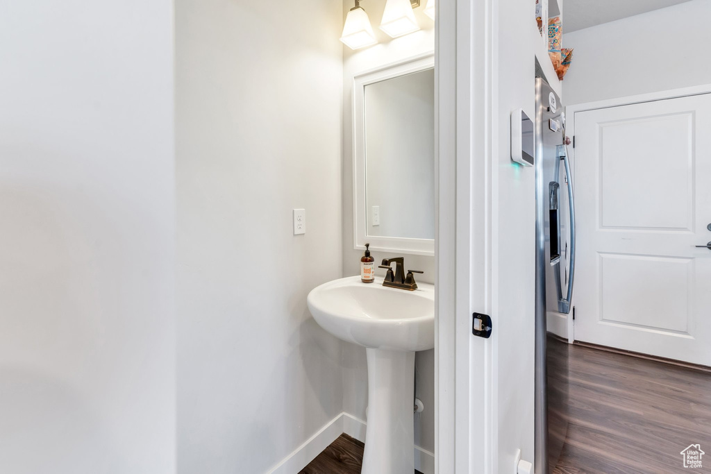 Bathroom featuring wood finished floors, a sink, and baseboards