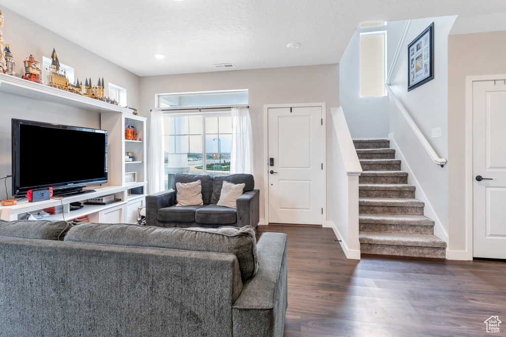 Living room featuring stairs, dark wood-style floors, baseboards, and recessed lighting