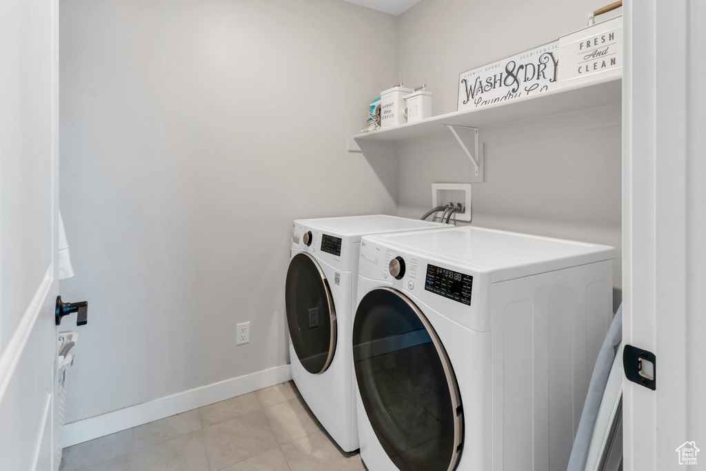Clothes washing area featuring washer and dryer, baseboards, and light tile patterned floors