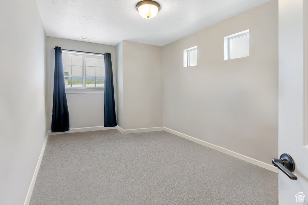 Carpeted empty room with baseboards and healthy amount of natural light