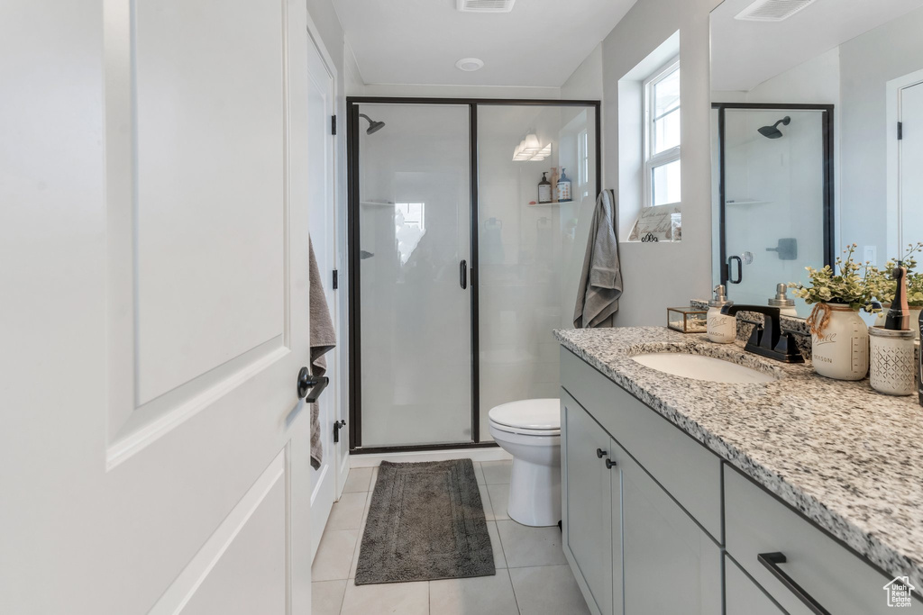 Bathroom with a stall shower, toilet, vanity, and tile patterned flooring