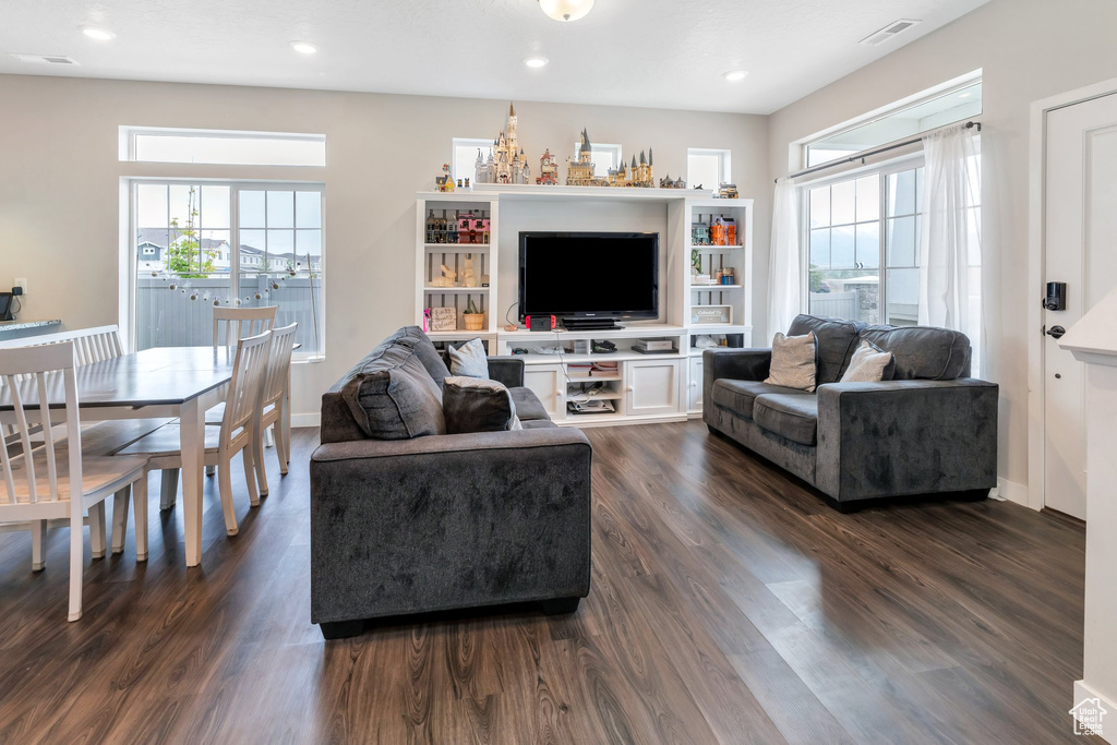 Living room featuring dark wood-type flooring, baseboards, and recessed lighting