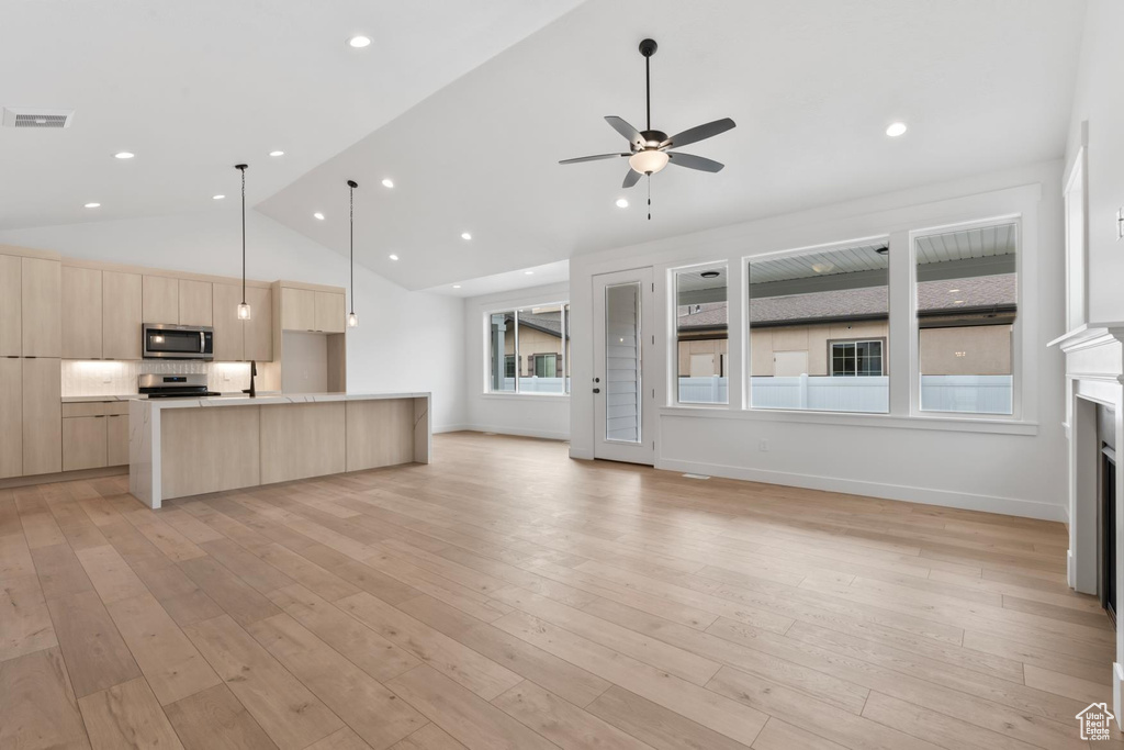 Unfurnished living room featuring high vaulted ceiling, a ceiling fan, light wood-style floors, a fireplace, and recessed lighting