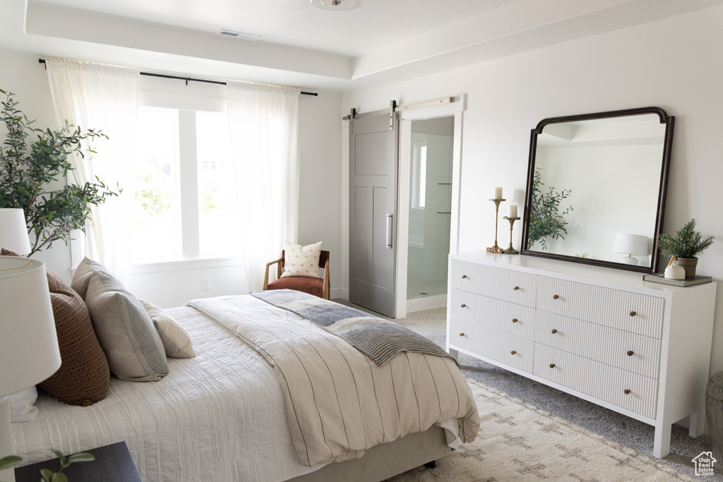 Bedroom featuring light colored carpet, a barn door, and connected bathroom