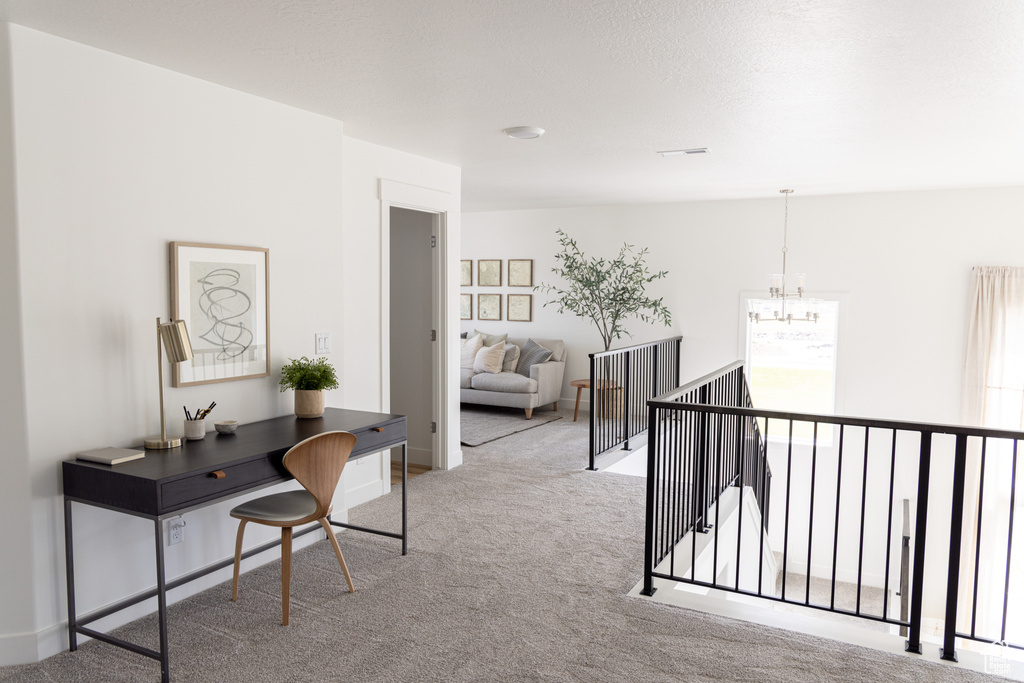 Hallway featuring an upstairs landing, carpet, and a chandelier