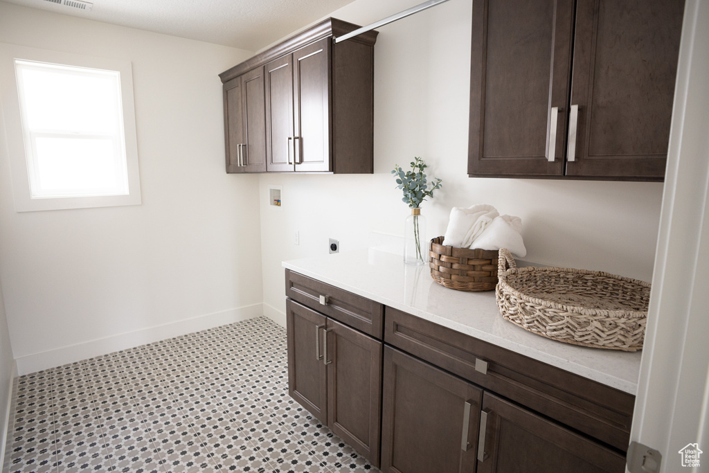 Laundry area with hookup for an electric dryer, cabinet space, washer hookup, baseboards, and light flooring