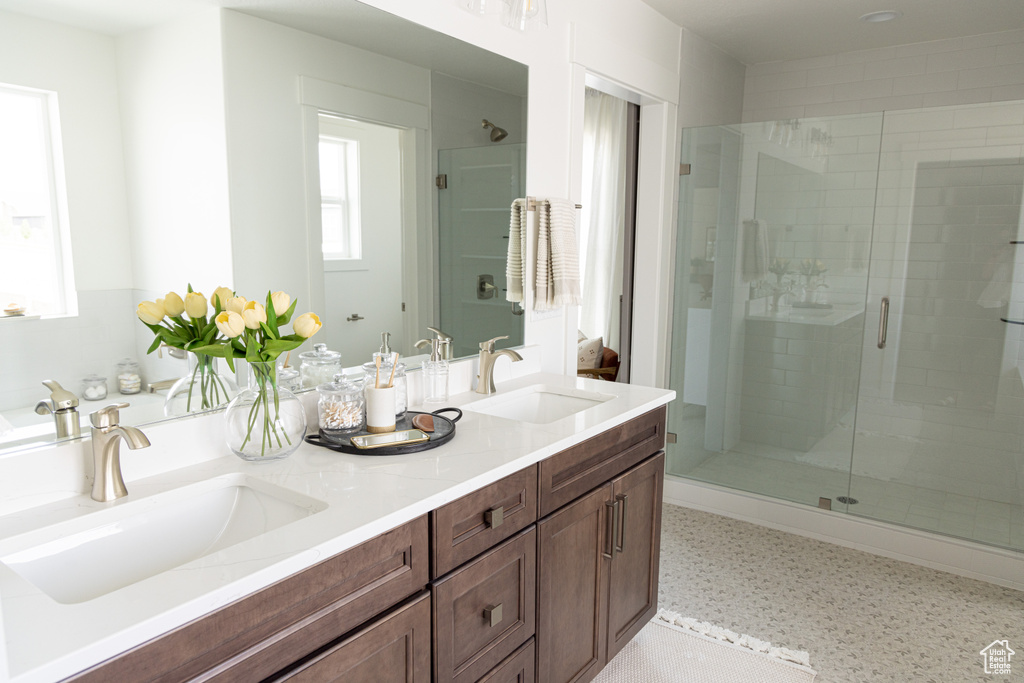 Bathroom featuring a stall shower, tile patterned floors, and double vanity