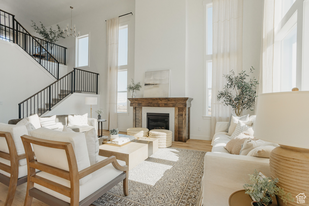 Living area featuring a high ceiling, wood finished floors, stairs, baseboards, and a glass covered fireplace