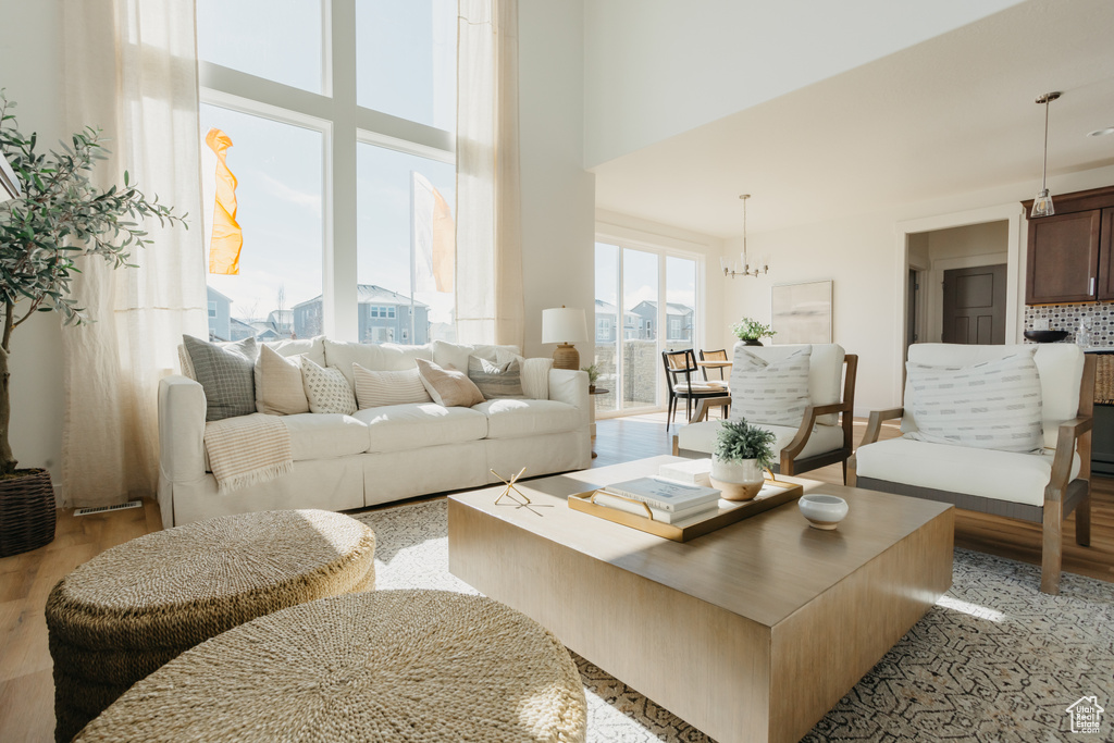 Living area with light wood-type flooring, a high ceiling, and a chandelier