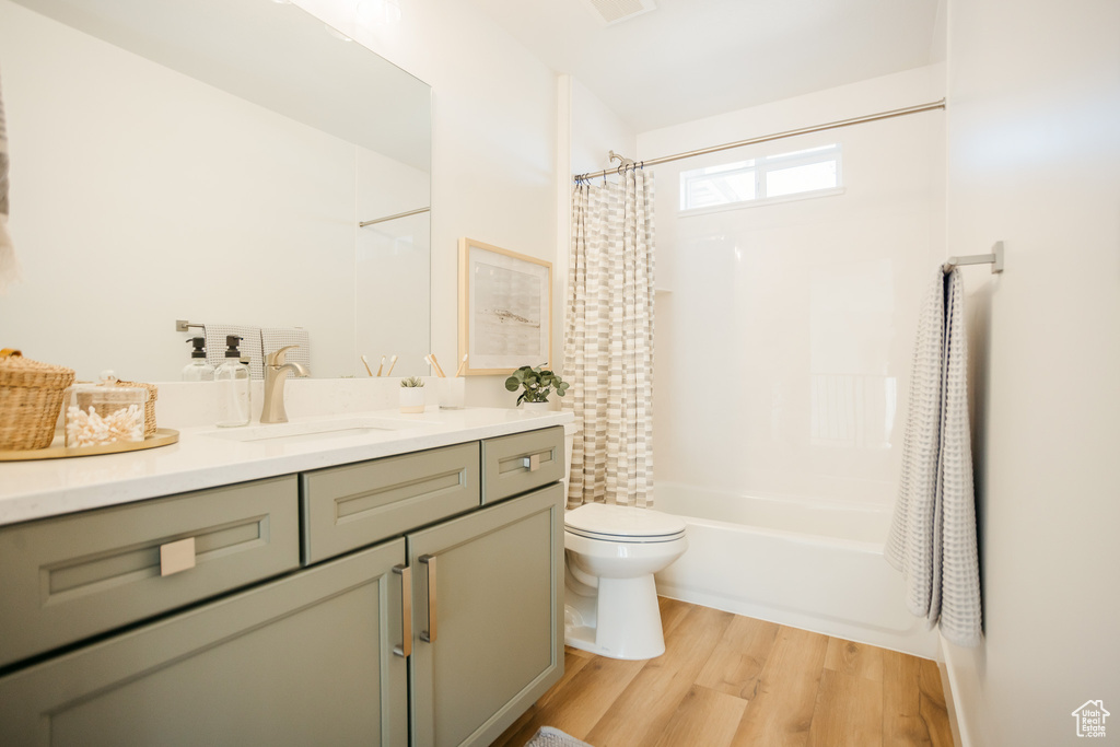 Bathroom featuring toilet, wood finished floors, vanity, and shower / tub combo