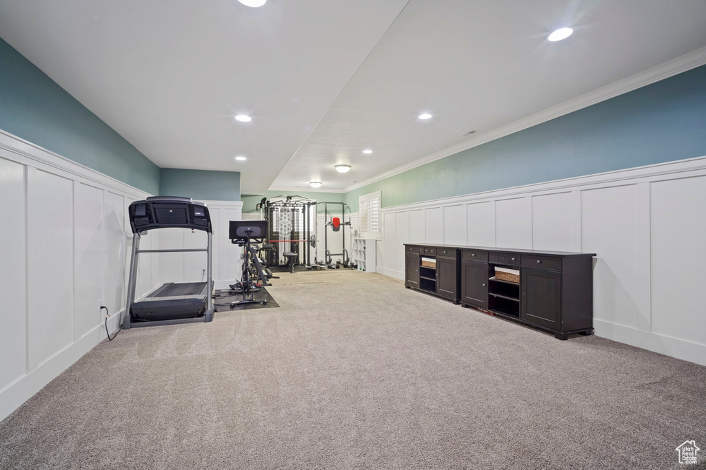 Exercise room with a decorative wall, carpet flooring, crown molding, recessed lighting, and wainscoting