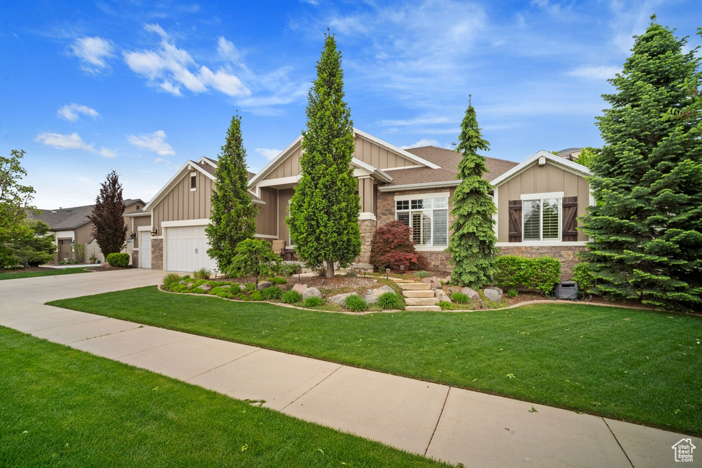 Craftsman-style home with board and batten siding, concrete driveway, an attached garage, and a front lawn