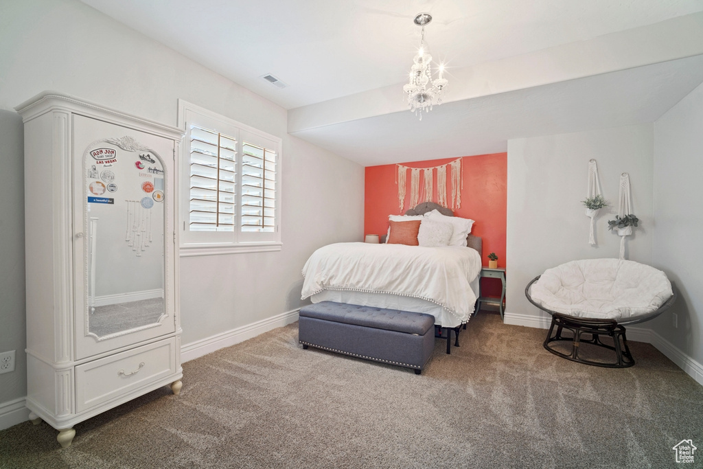 Carpeted bedroom featuring baseboards and a chandelier