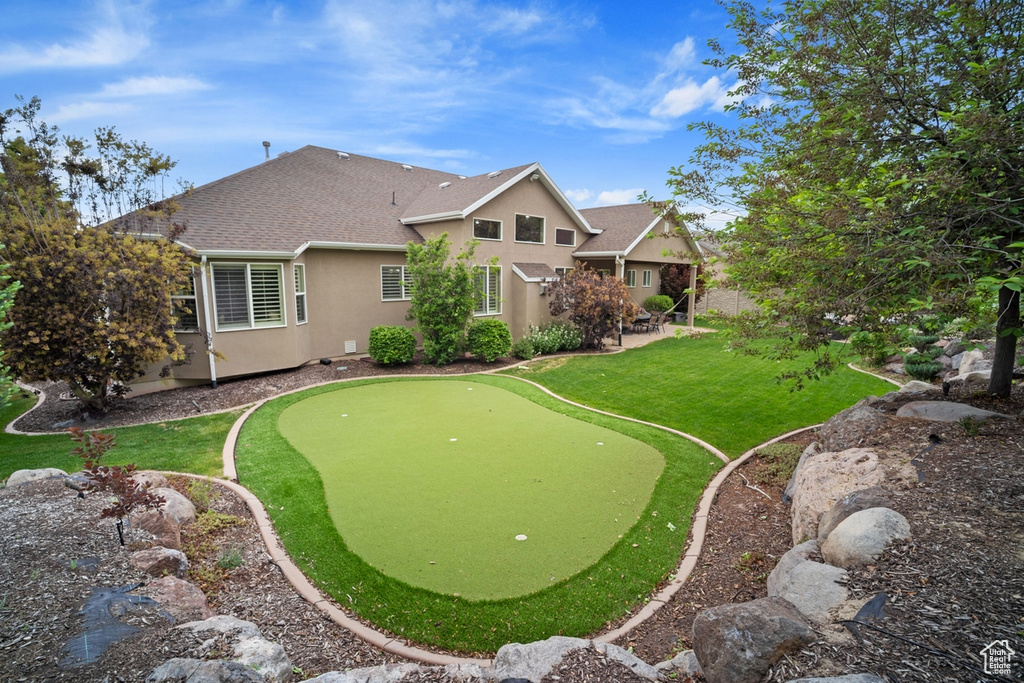 View of property\'s community with an area to practice putting, a patio area, and a yard
