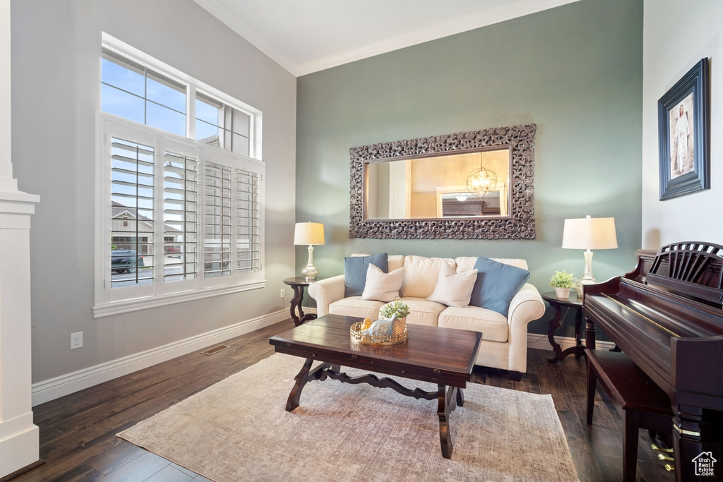 Living area with wood finished floors, healthy amount of natural light, ornamental molding, and baseboards