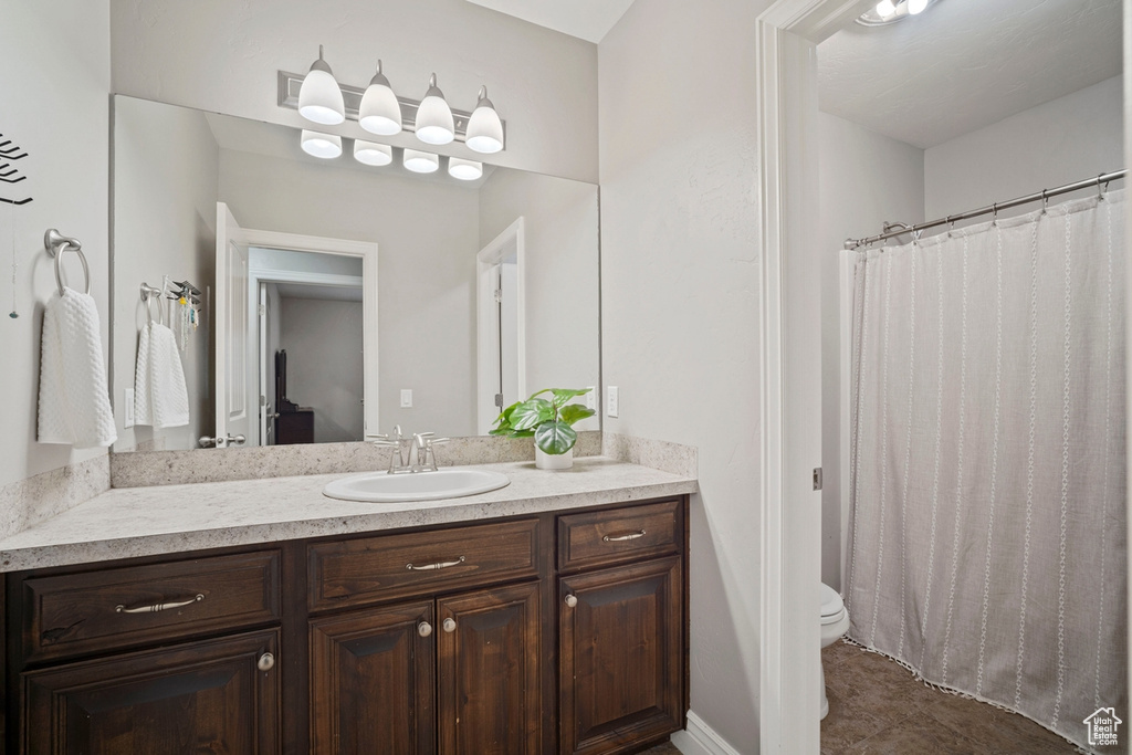 Full bath featuring toilet, vanity, and curtained shower