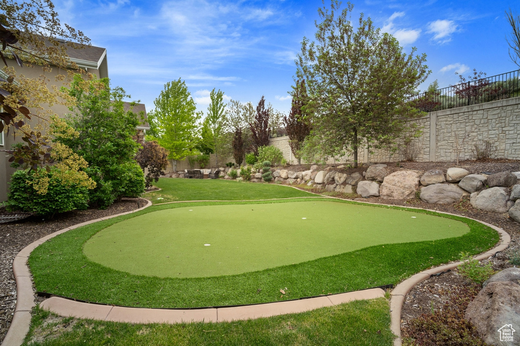 View of home\'s community with a putting green and a fenced backyard