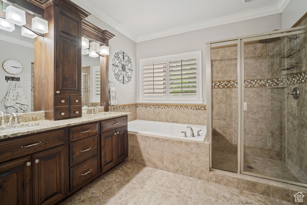 Full bath featuring a stall shower, a bath, double vanity, crown molding, and plenty of natural light