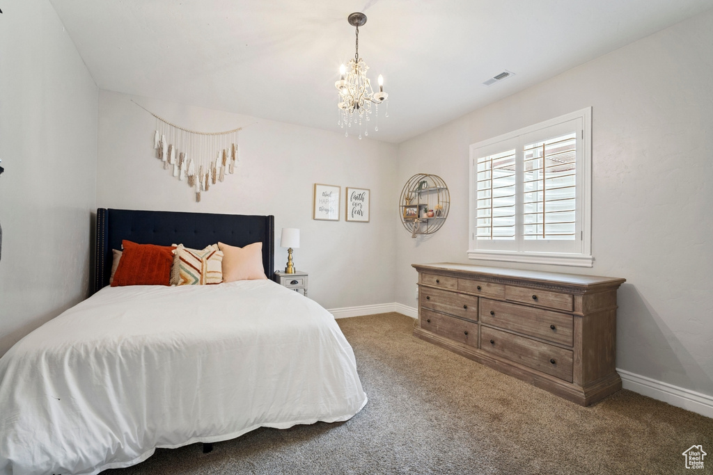 Carpeted bedroom with a chandelier and baseboards