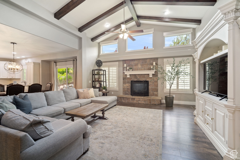 Living room featuring a chandelier, a stone fireplace, ceiling fan, dark wood-style flooring, and recessed lighting