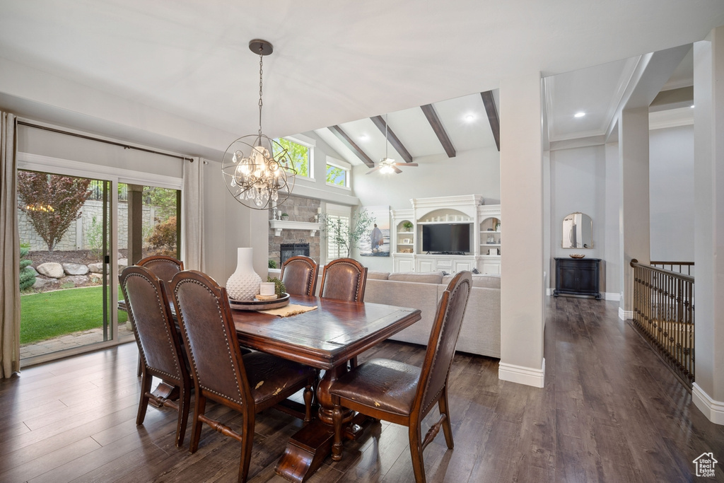 Dining space featuring a stone fireplace, beam ceiling, plenty of natural light, dark wood-style flooring, and high vaulted ceiling