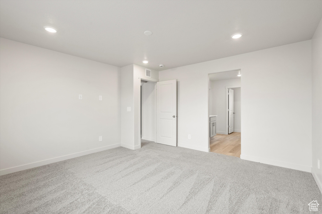 Unfurnished bedroom with light colored carpet and recessed lighting