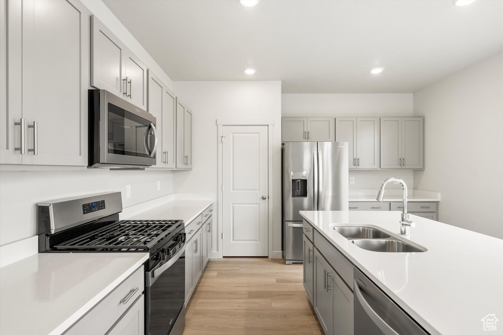 Kitchen with appliances with stainless steel finishes, gray cabinetry, recessed lighting, light wood-style floors, and light countertops
