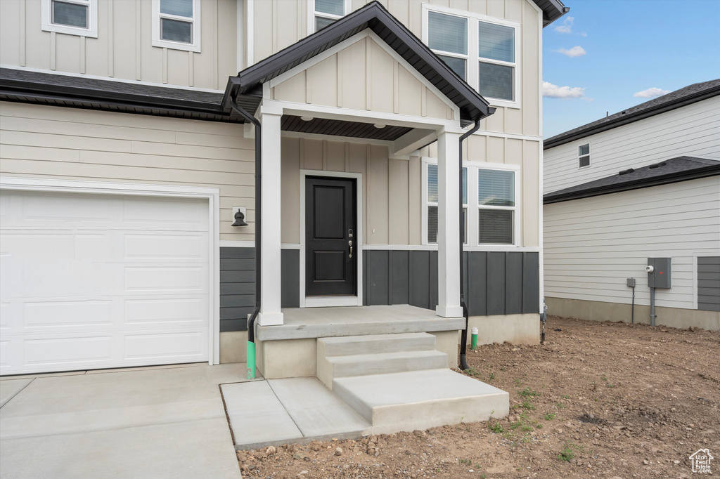 View of exterior entry with board and batten siding and concrete driveway