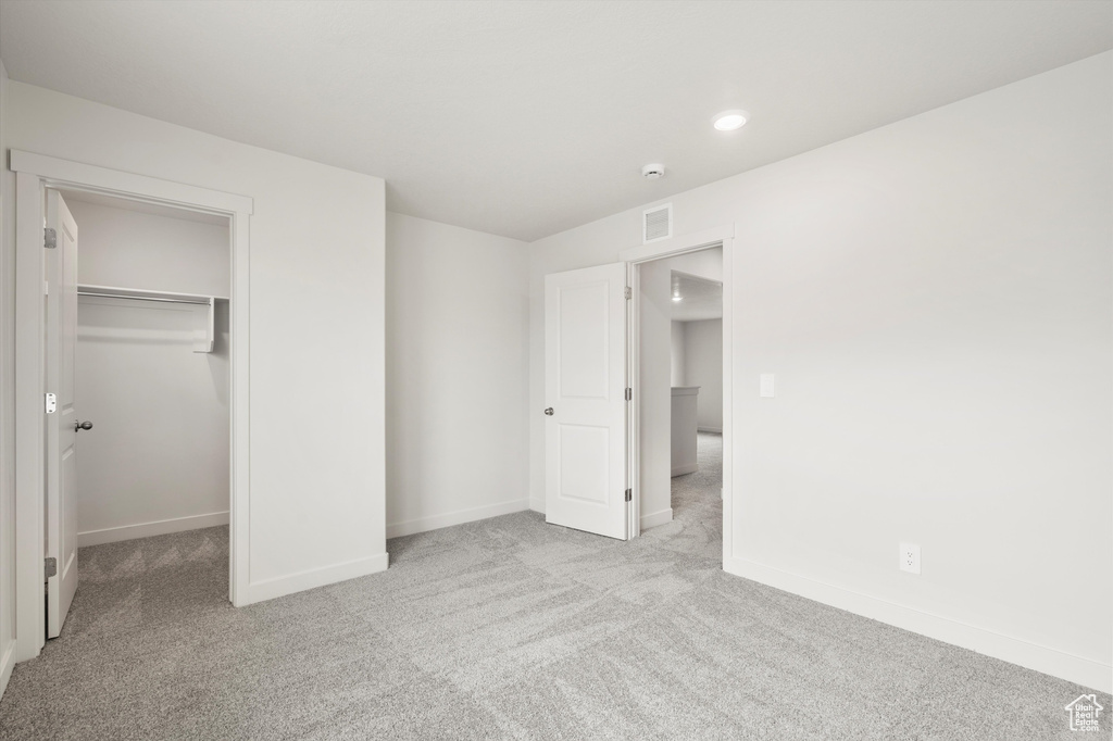 Unfurnished bedroom with carpet, a spacious closet, recessed lighting, and a closet