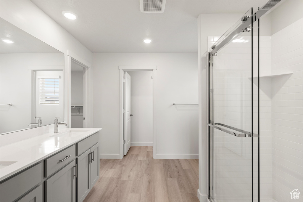Bathroom with a stall shower, wood finished floors, double vanity, and recessed lighting