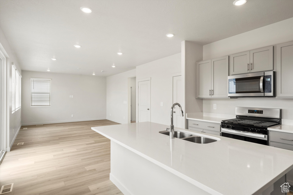 Kitchen featuring appliances with stainless steel finishes, gray cabinetry, light wood-style floors, light countertops, and recessed lighting