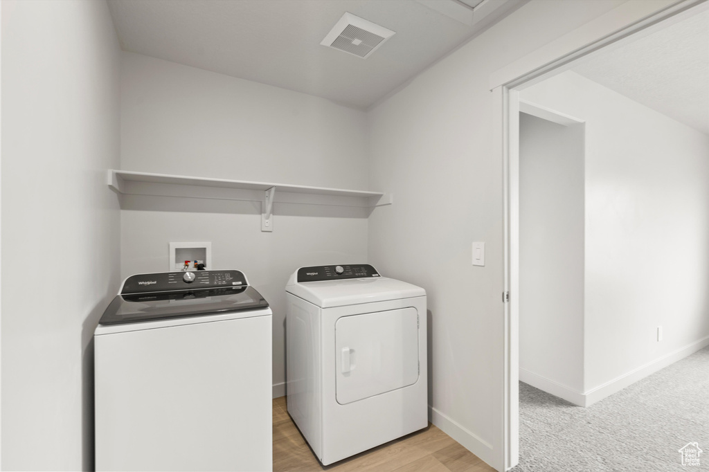 Washroom featuring washing machine and clothes dryer and light wood finished floors