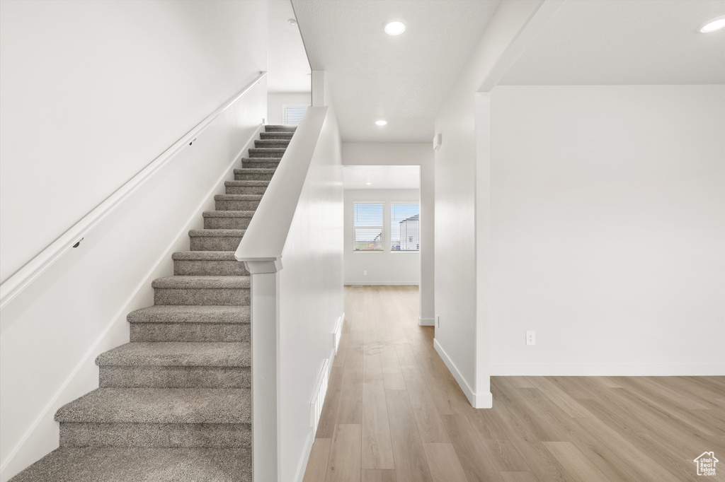 Stairs with wood finished floors and recessed lighting