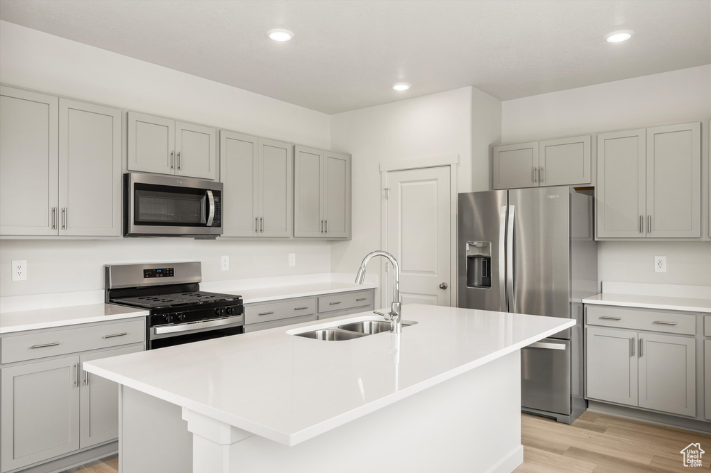Kitchen with appliances with stainless steel finishes, gray cabinets, light wood-type flooring, recessed lighting, and light countertops