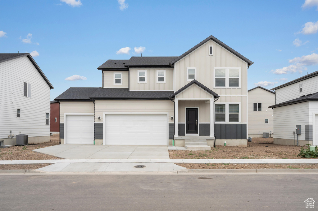 View of front of property with board and batten siding, concrete driveway, and a garage