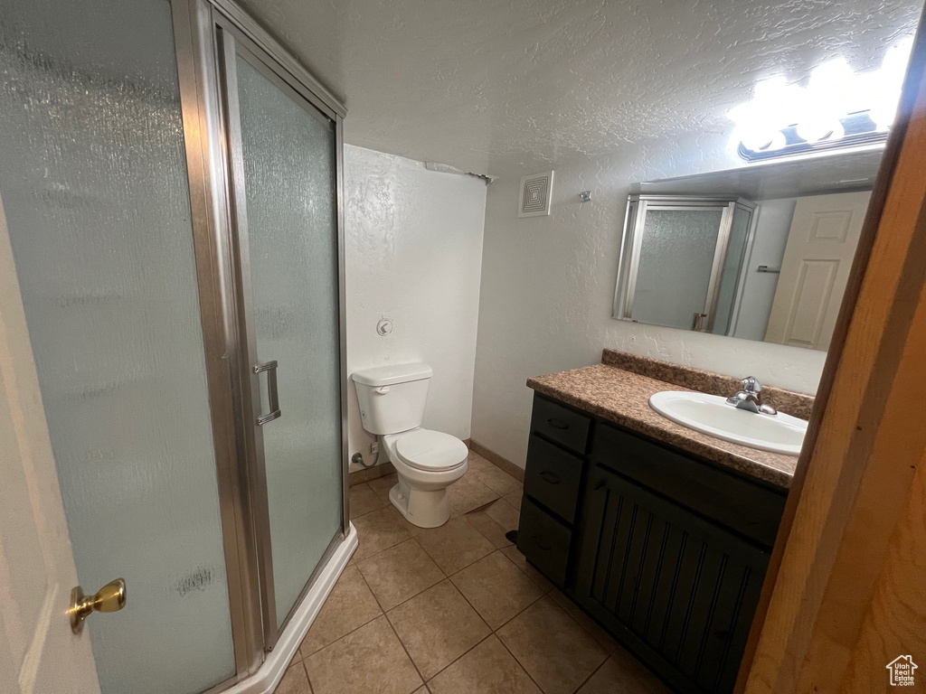 Full bath featuring tile patterned flooring, a shower stall, toilet, and vanity