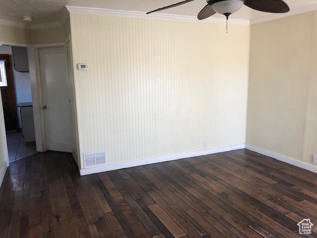Spare room with ceiling fan, dark wood finished floors, crown molding, and baseboards