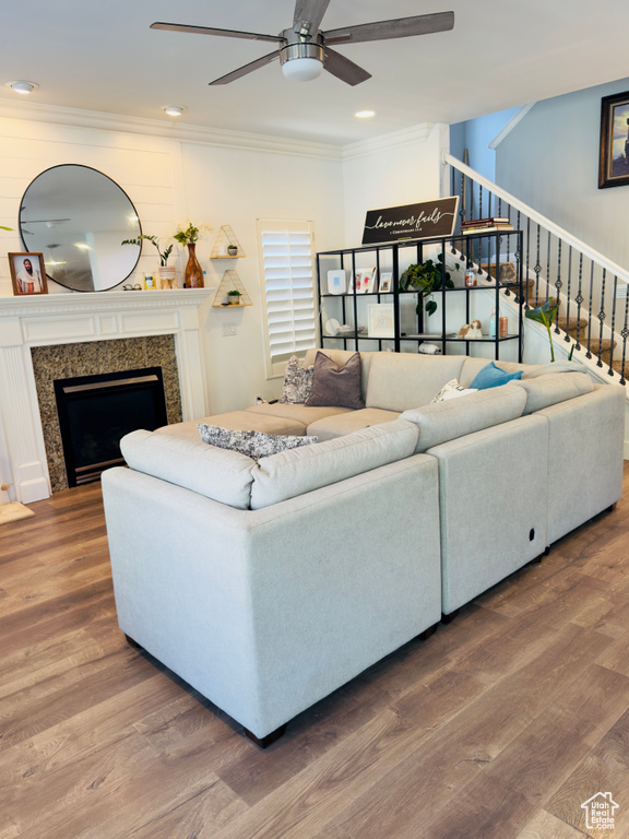 Living area with ceiling fan, crown molding, stairway, a fireplace, and wood finished floors
