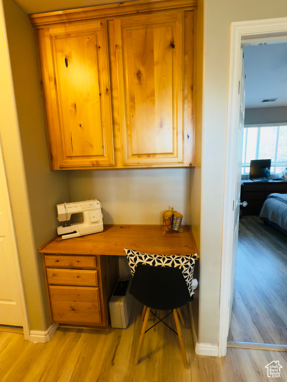 Office area with built in desk, light wood-style flooring, and baseboards