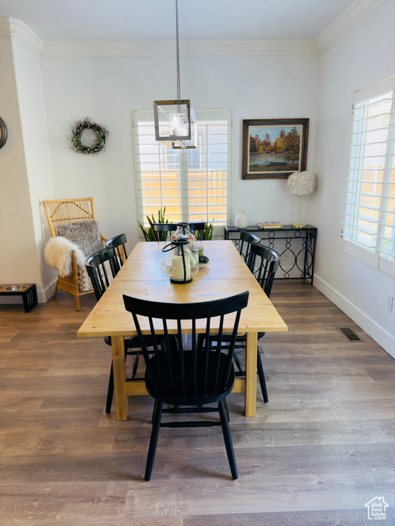 Dining area with ornamental molding, baseboards, and wood finished floors