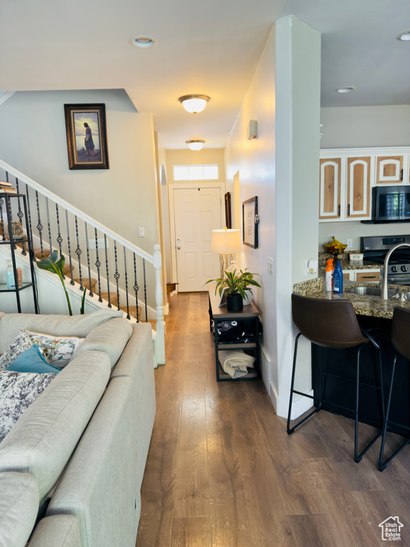 Living area with stairway, baseboards, dark wood-type flooring, and recessed lighting