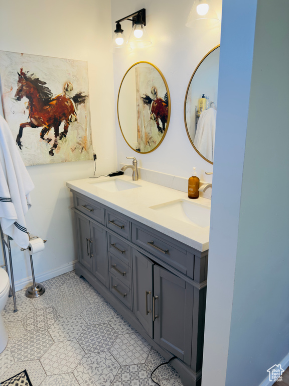 Bathroom with double vanity, toilet, and baseboards