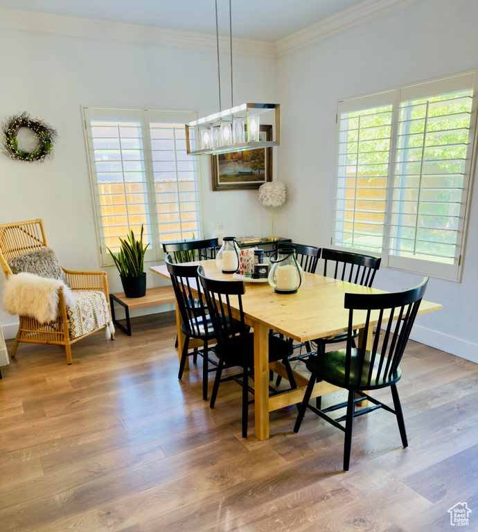 Dining area featuring healthy amount of natural light, ornamental molding, wood finished floors, and baseboards