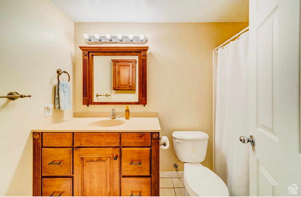 Full bathroom with tile patterned floors, vanity, toilet, and baseboards