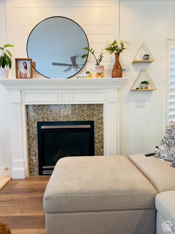 Detailed view of wood finished floors, a ceiling fan, and a fireplace